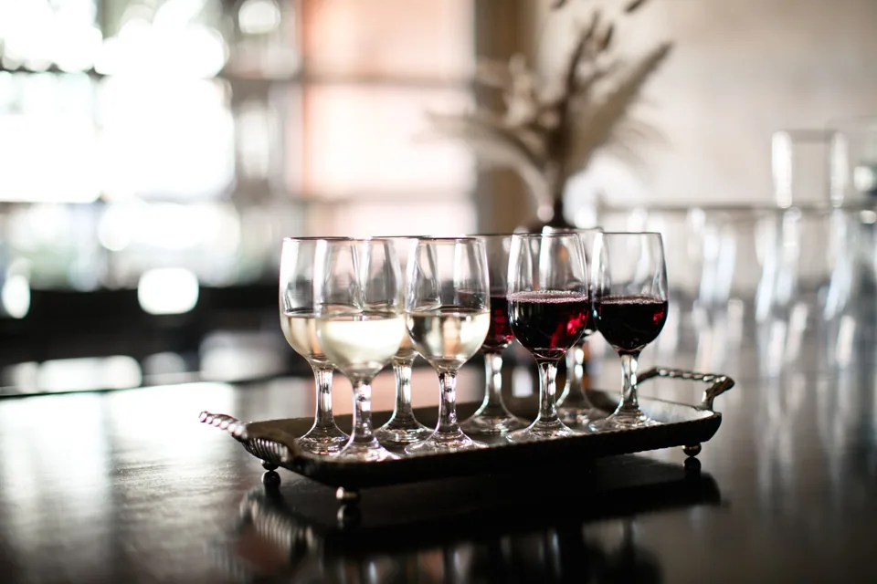 Glasses of white and red wine lined up on a silver serving tray